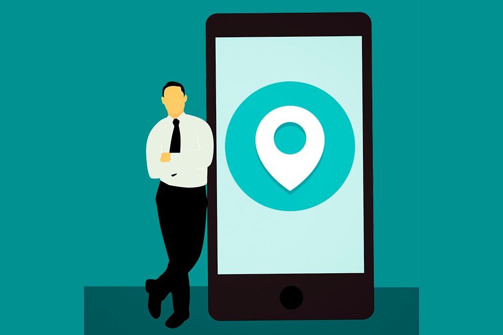 En la imagen se muestra un hombre junto a un smartphone, de su mismo tamaño, que muestra el icono asociado a una localización física en Google Maps o servicio similar - 10 consejos para mejorar tus ventas con Google My Business