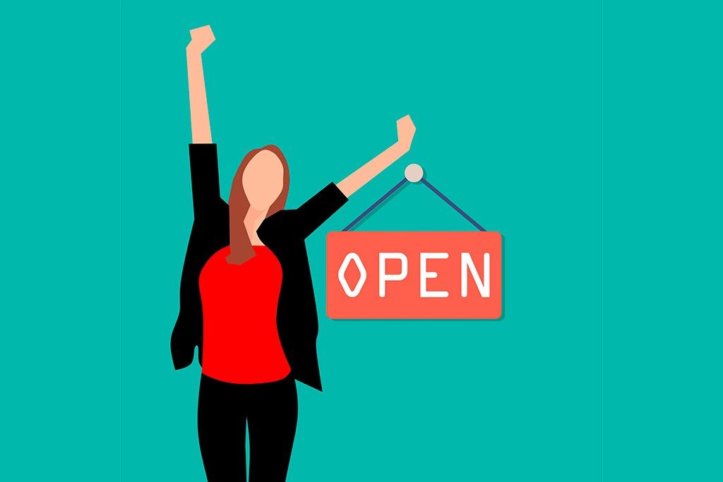 En la imagen vemos una mujer con los brazos abiertos en gesto de triunfo con un cartel que pone "Open" (abierto) indicándonos que ha abierto un negocio y su ilusión por ello - 10 consejos para mejorar tus ventas con Google My Business